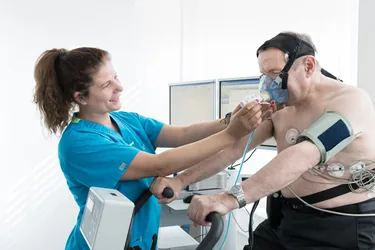 Spiroergometrie mit Atemmaske auf dem Fahrradergometer, begleitet von einer Praxisassistentin