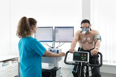 Spiroergometrie auf dem Fahrradergometer, begleitet von einer medizinischen Praxisassistentin